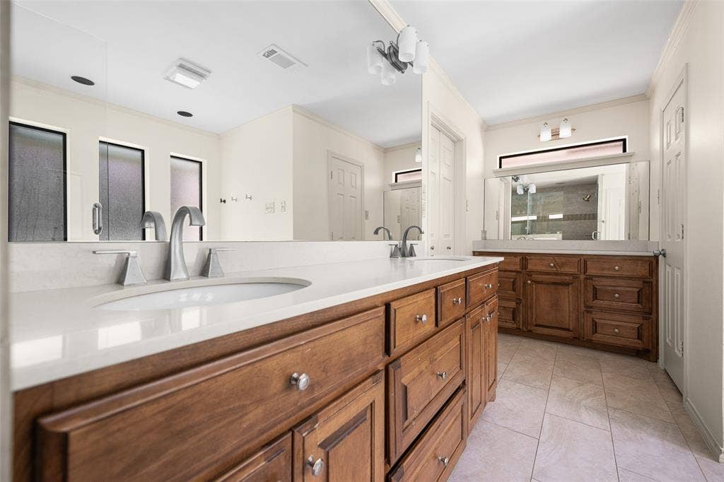 6501 Copper Creek Drive, Dallas, TX 75248 Double vanity featuring wood cabinetry, white stone countertops, and undermount sinks