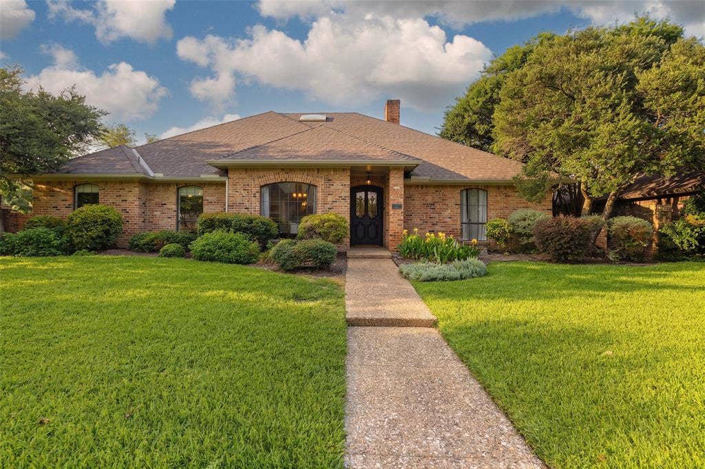 6501 Copper Creek Drive, Dallas, TX 75248 Traditional brick exterior with a dark entry door, arched window, and mature landscaping