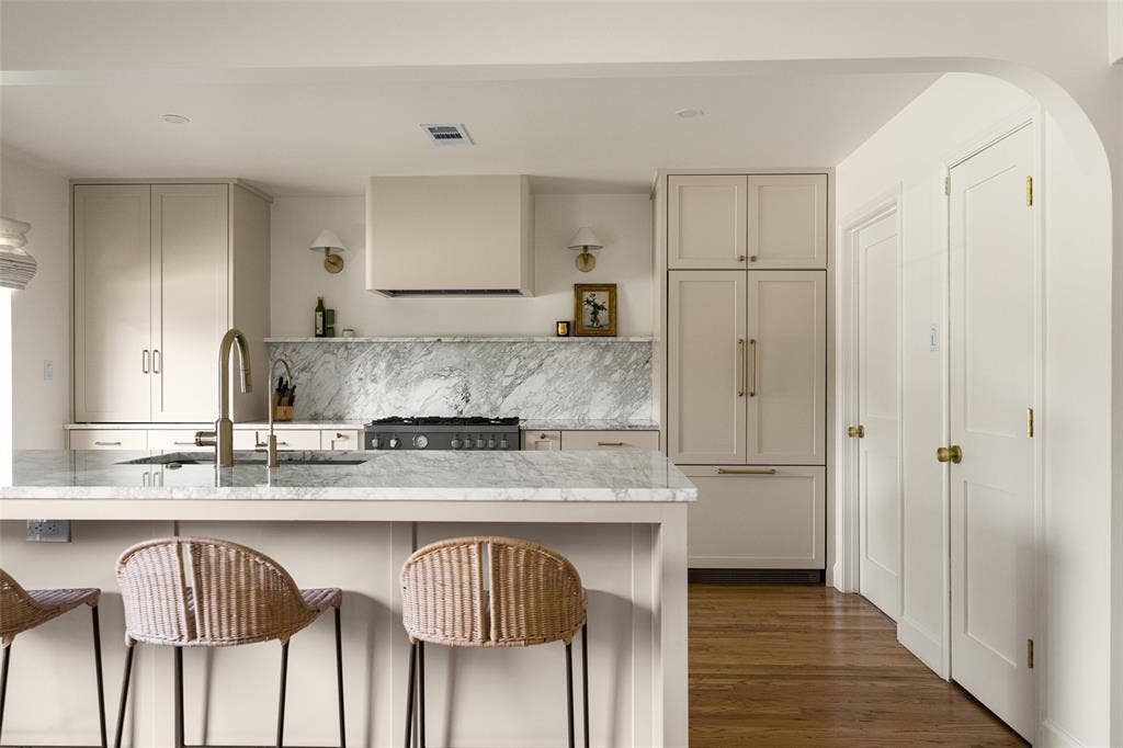 6501 Copper Creek Drive, Dallas, TX 75248 Kitchen featuring light-toned cabinetry, a large center island with a built-in sink, stone countertops and backsplash, a professional-grade range with a custom hood, and integrated refrigeration