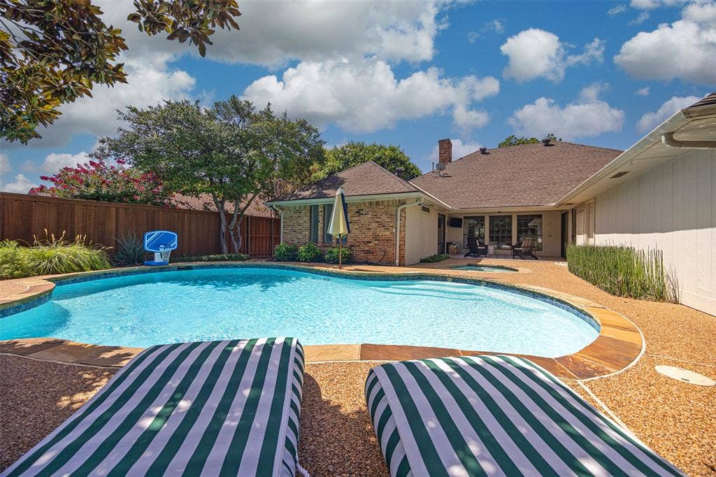 6501 Copper Creek Drive, Dallas, TX 75248 Outdoor swimming pool with a curved perimeter and integrated spa, surrounded by an exposed aggregate patio