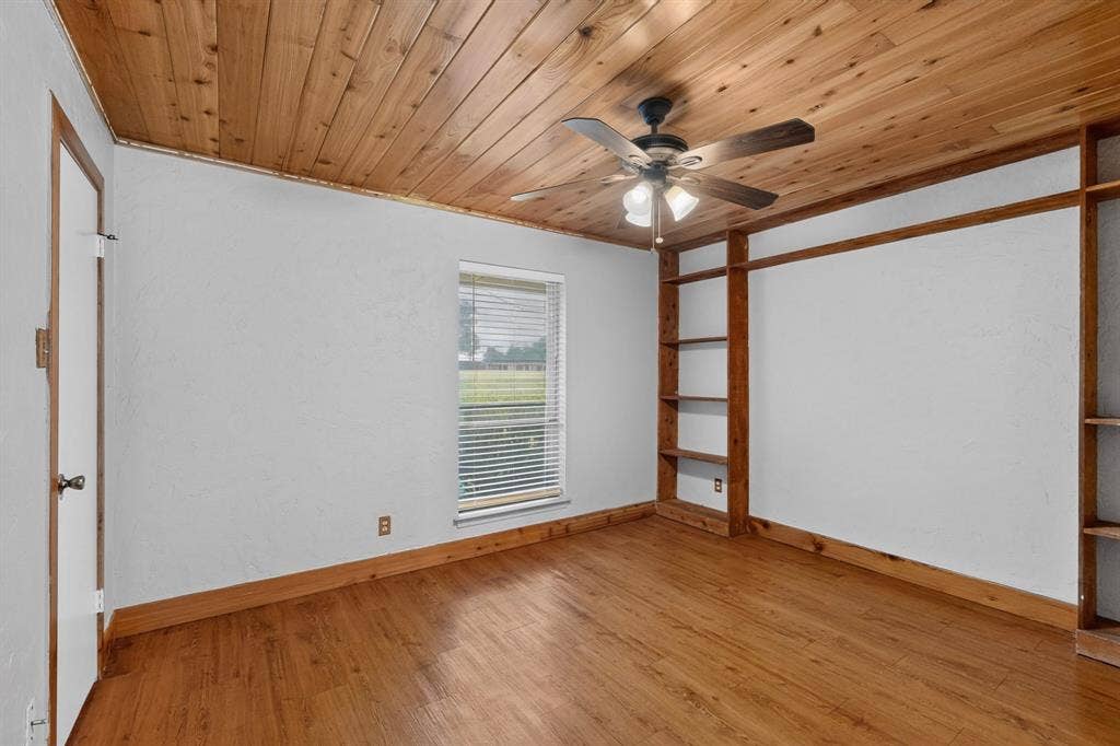 Room featuring a wood-panel ceiling, wood-finish flooring, and white walls