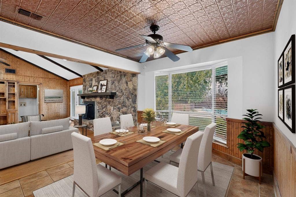 Dining area featuring a pressed metal ceiling, a bay window with horizontal blinds, and tile flooring