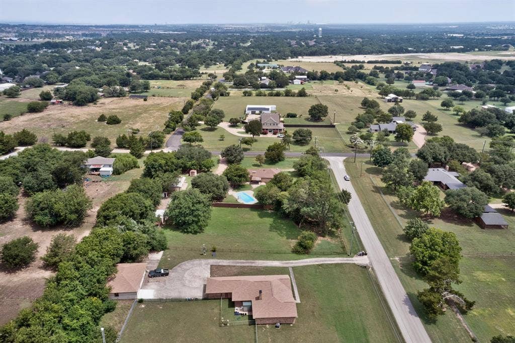 Aerial perspective showcasing the surrounding landscape with residential properties and abundant mature trees