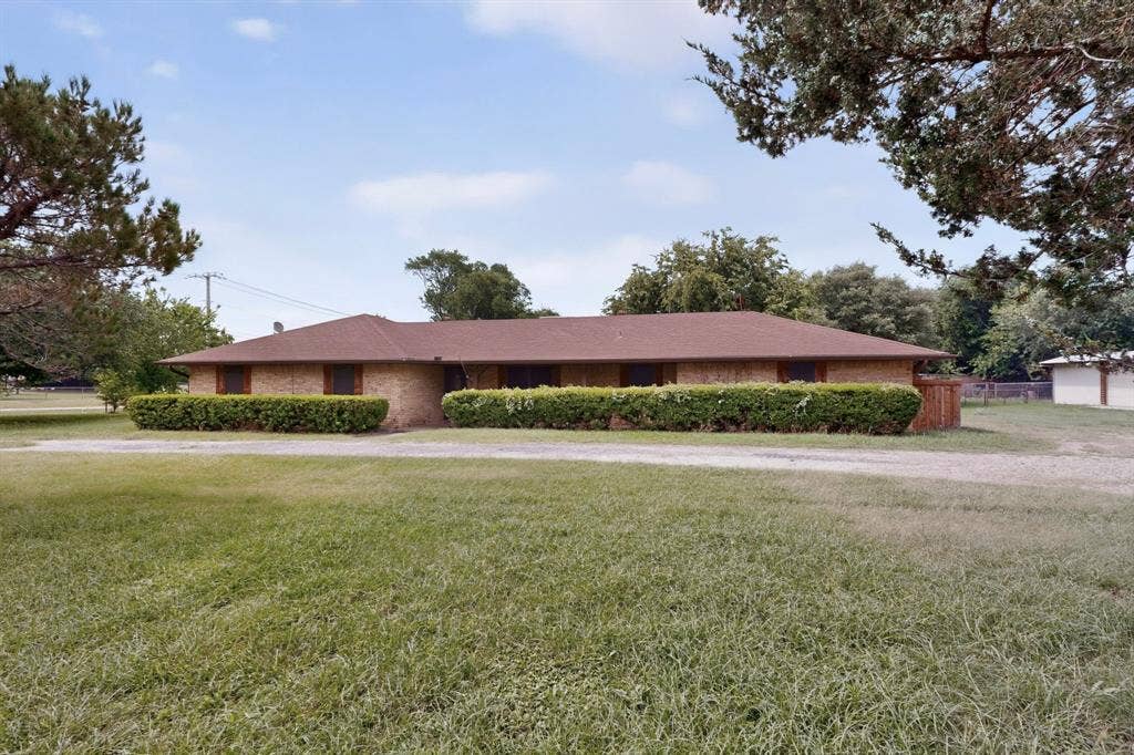 Brick ranch-style exterior with a low-pitch roof and dark brown shingles