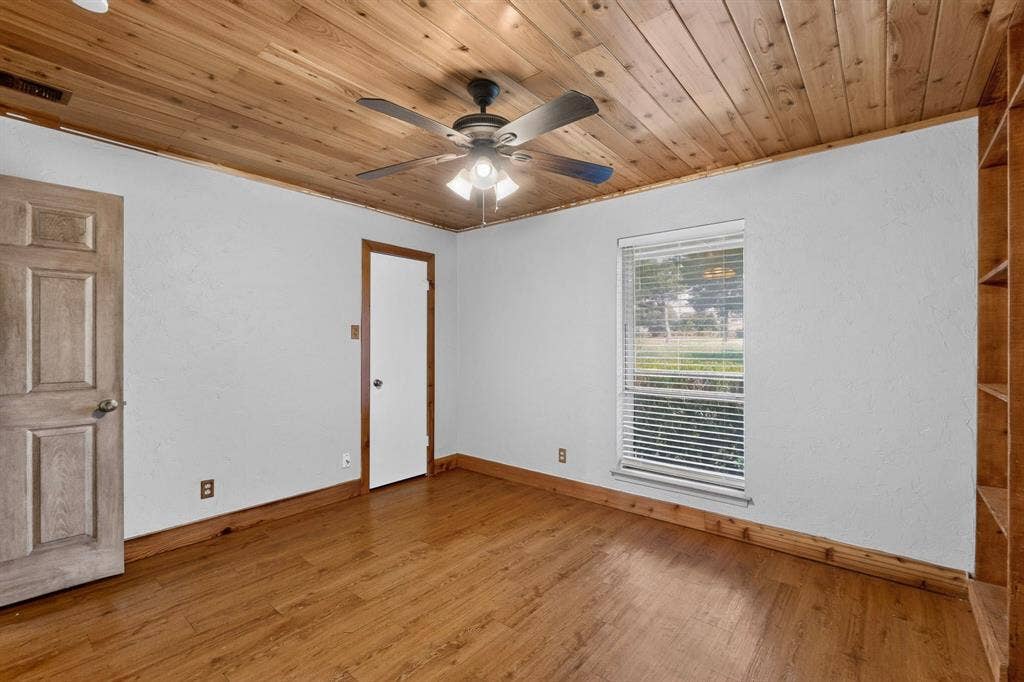 Room featuring a wood-panel ceiling, wood-finish flooring, and white walls