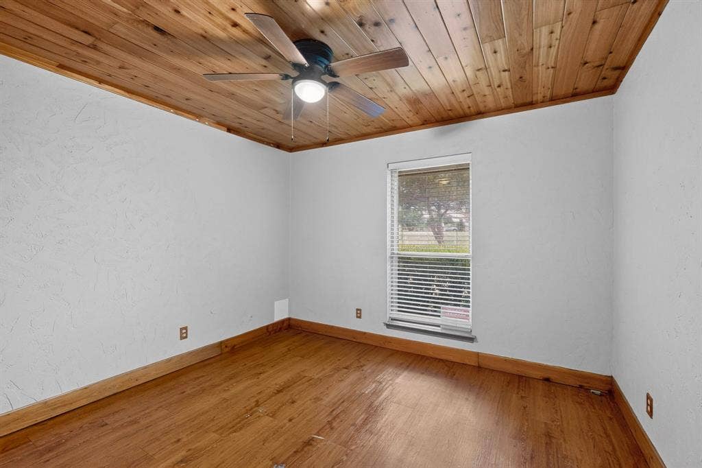 Room featuring a wood-panel ceiling, wood-finish flooring, and white walls
