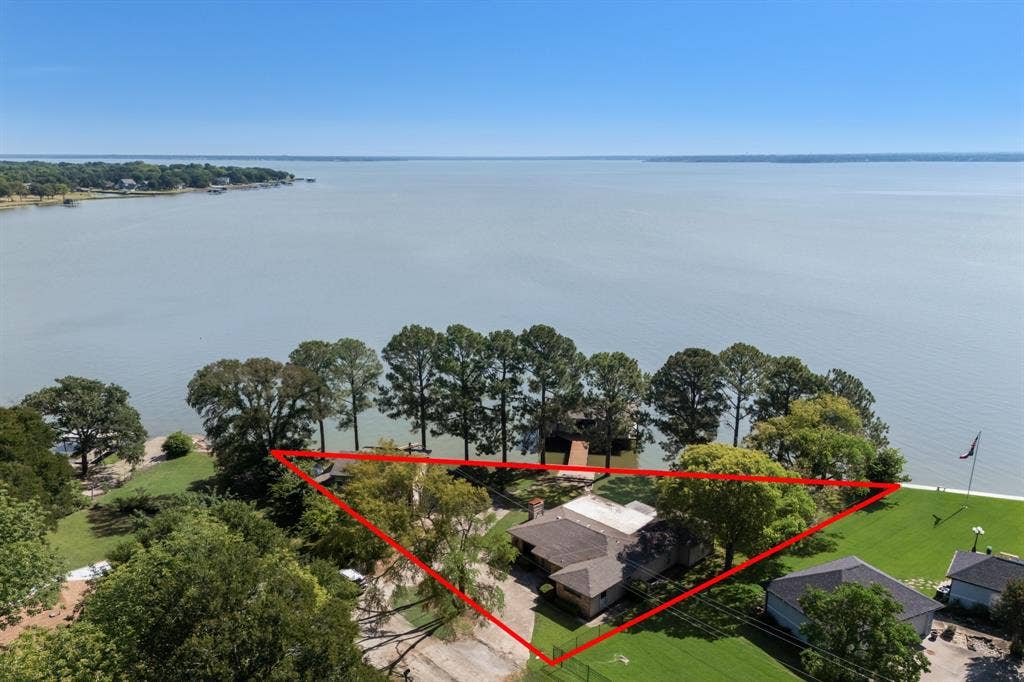 Expansive waterfront property featuring a substantial body of water, mature trees, and a private dock structure