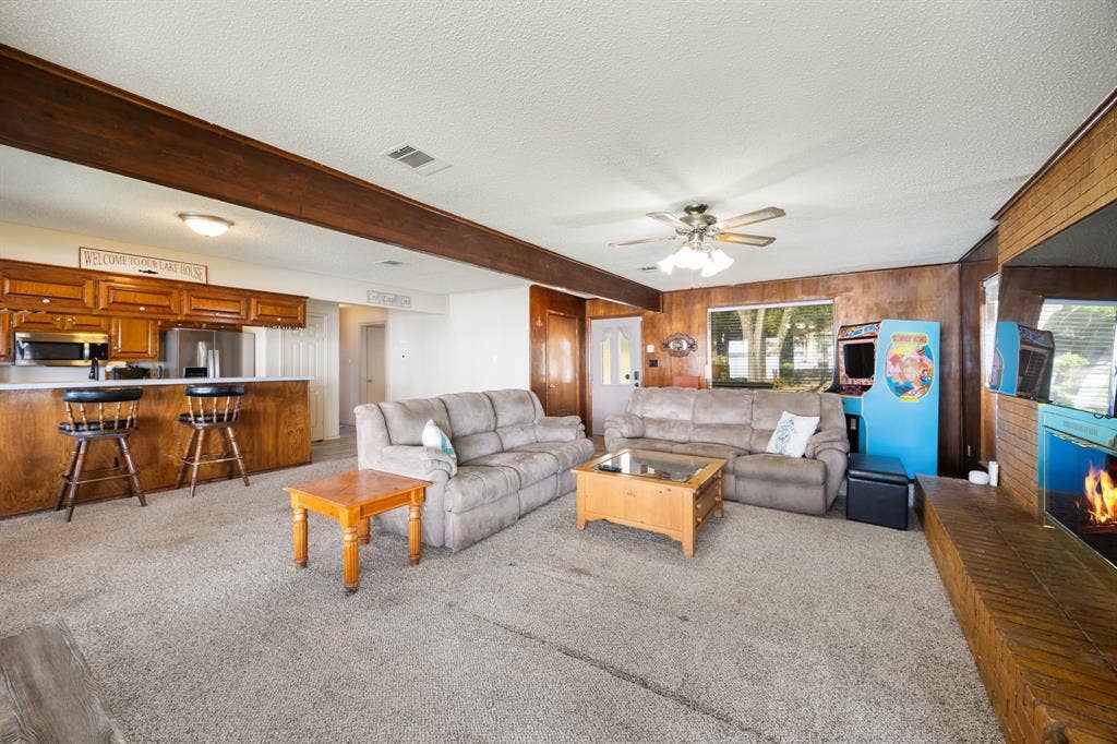 living area featuring a breakfast bar with built-in cabinetry, wood-paneled walls, and a ceiling fan