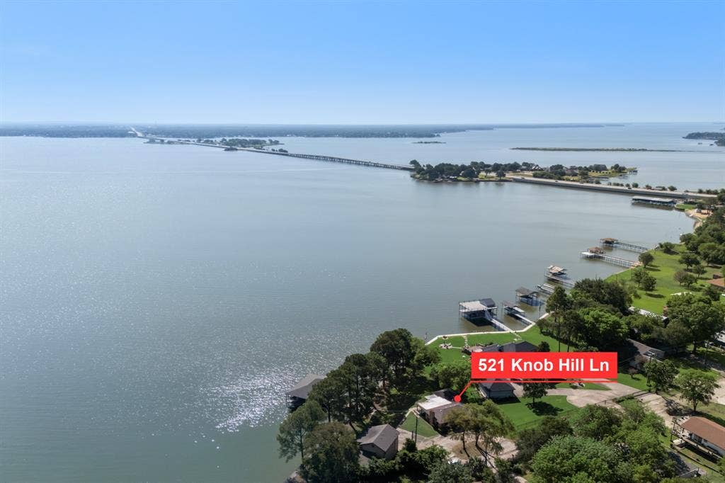 Waterfront property featuring multiple boat docks, mature trees, and a spacious green lawn