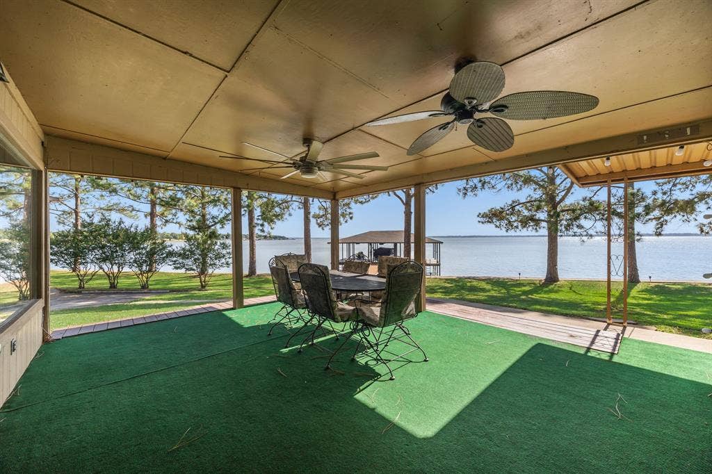 Covered patio with green outdoor carpeting, two ceiling fans, and expansive water frontage