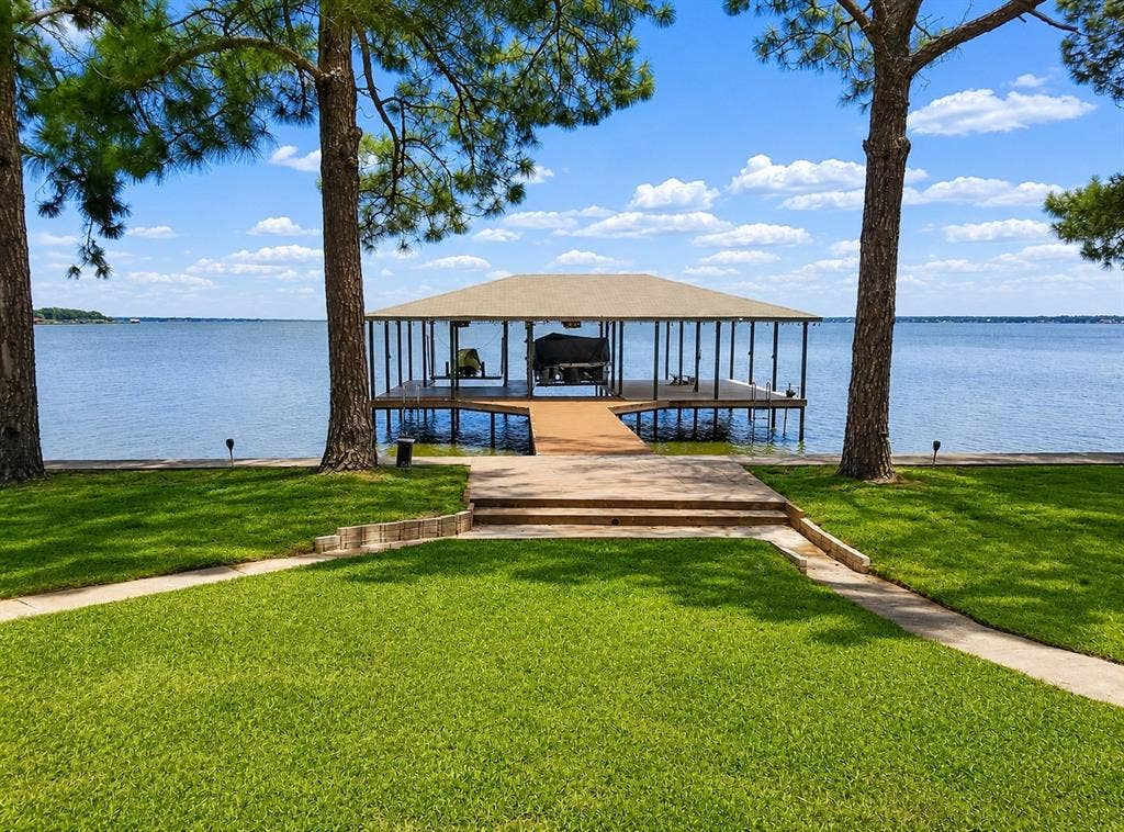 Covered boat dock featuring a boat lift and access ramp