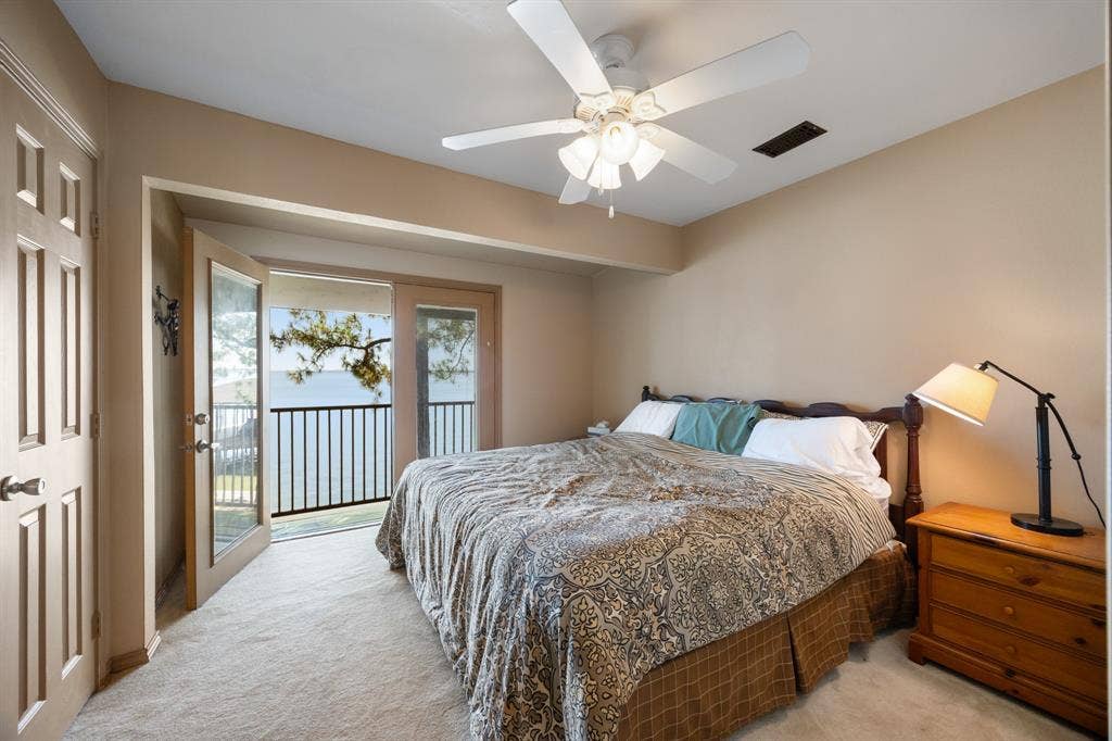 Bedroom featuring French doors opening to a balcony with metal railings and water scenery
