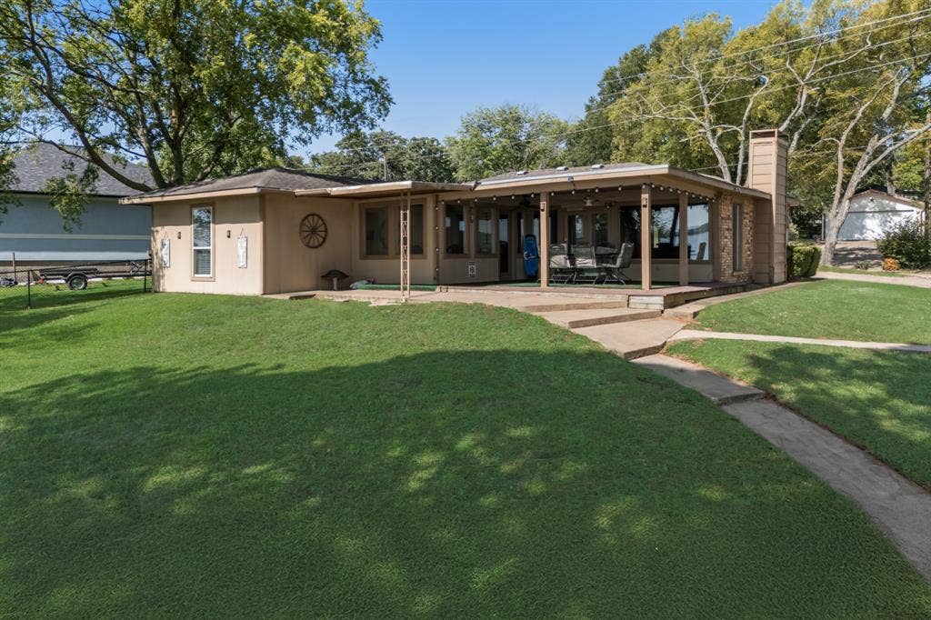Rear exterior with a concrete patio, covered porch area, and expansive green lawn