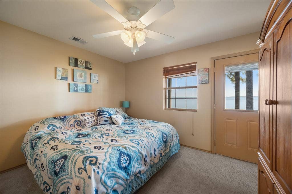 Room with a window and glass-paneled door offering exterior water scenery