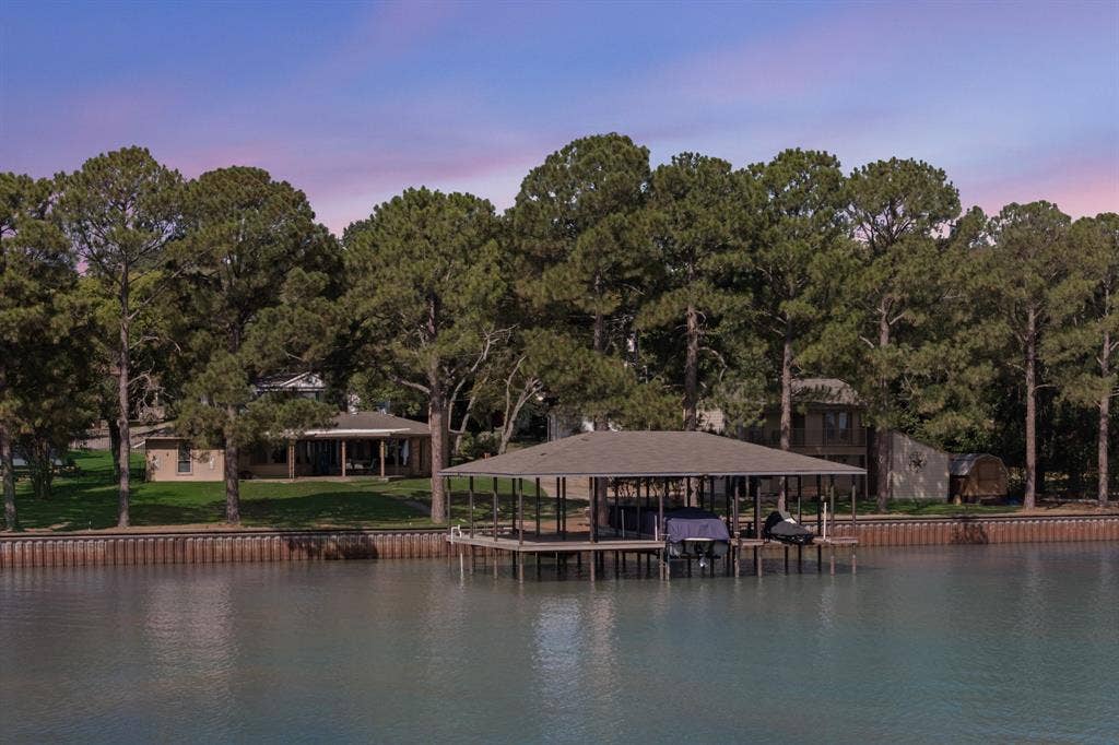 Waterfront property featuring a covered boat dock, substantial bulkhead, and mature trees