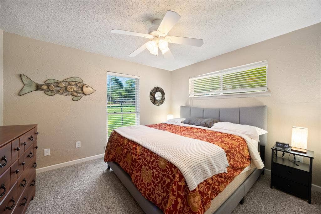 Bedroom featuring a textured ceiling, ceiling fan, and carpeted flooring
