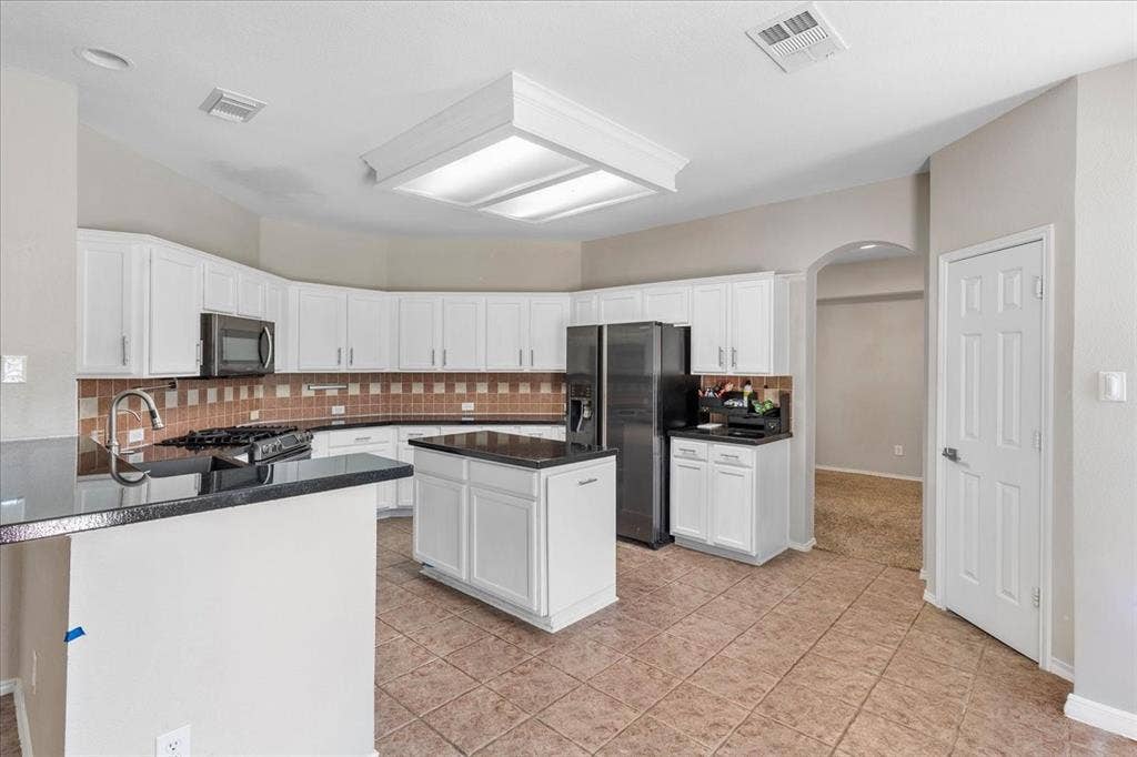 1013 Larkspur Drive, Allen, TX 75002 Kitchen featuring white cabinetry, a central island, dark countertops, and a tile backsplash