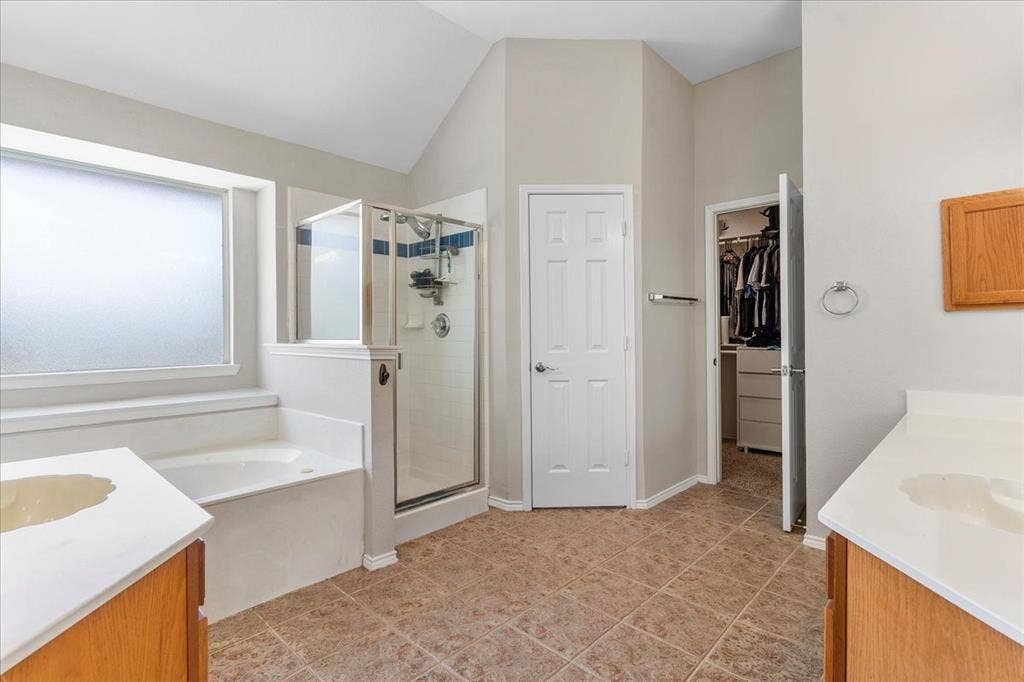 1013 Larkspur Drive, Allen, TX 75002 Bathroom featuring a separate shower enclosure with glass surround, a built-in soaking tub, and dual vanity areas with wood cabinetry