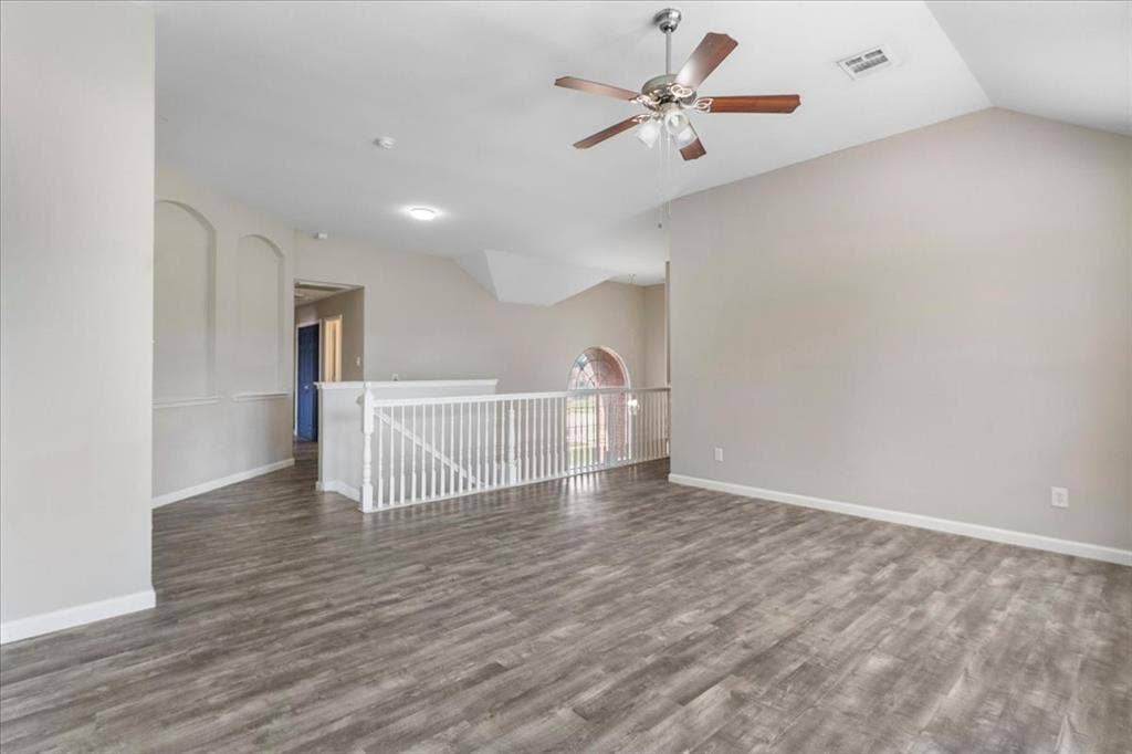 1013 Larkspur Drive, Allen, TX 75002 Spacious room featuring vaulted ceilings, wood-finish flooring, a contemporary ceiling fan, and a white balustrade overlooking a lower level