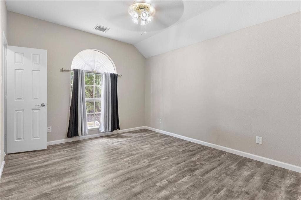 1013 Larkspur Drive, Allen, TX 75002 Spacious room featuring vaulted ceilings, wood-finish flooring, a large arched window, and a ceiling fan with integrated lighting