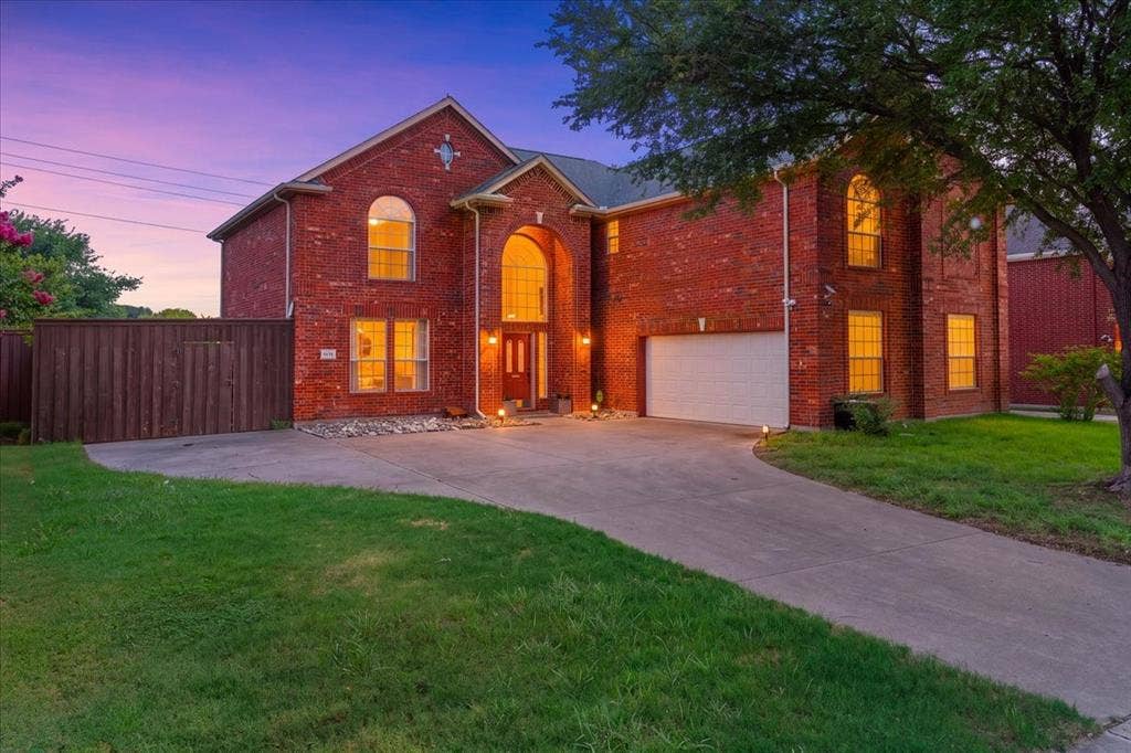 1013 Larkspur Drive, Allen, TX 75002 Brick exterior featuring an arched entryway with double doors, arched windows, an attached garage, and a concrete driveway