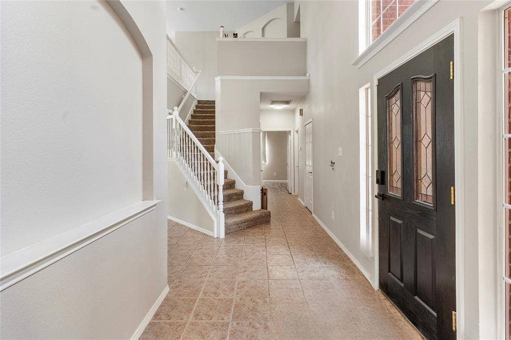 1013 Larkspur Drive, Allen, TX 75002 Entryway featuring a dark wood-finish door with decorative glass inserts, tile flooring, and a two-story ceiling