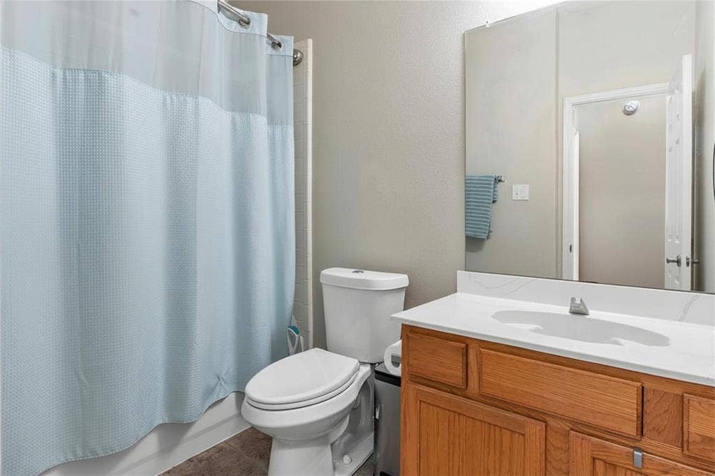1013 Larkspur Drive, Allen, TX 75002 Spacious bathroom featuring a wood-finish vanity with dual-sink countertop, large framed mirror, and ample storage