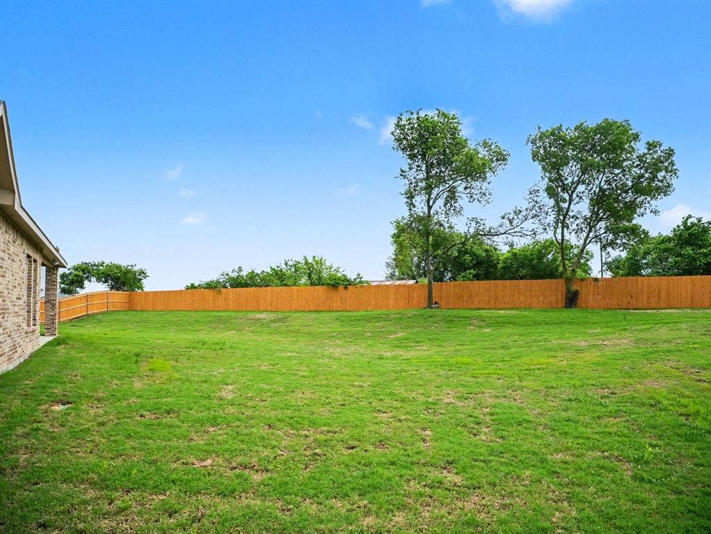 Expansive lawn area featuring a newly installed privacy fence
