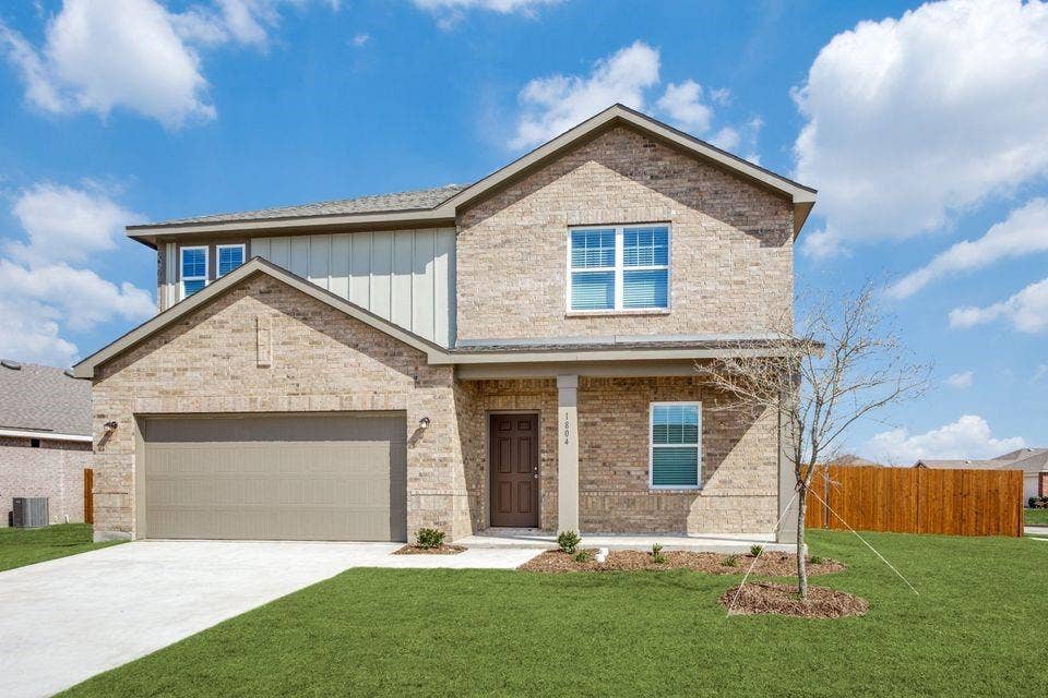 Two-story residence featuring a brick facade, covered front entry, attached garage with concrete driveway, and a fenced backyard