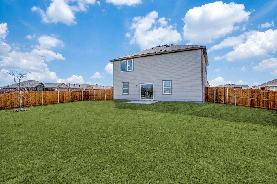 Expansive rear yard featuring a privacy fence, a concrete patio, and a two-story exterior with siding