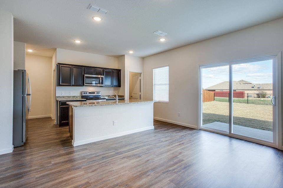Open concept living space featuring wood-finish flooring, a kitchen island with stone countertops, dark wood cabinetry, and stainless steel appliances