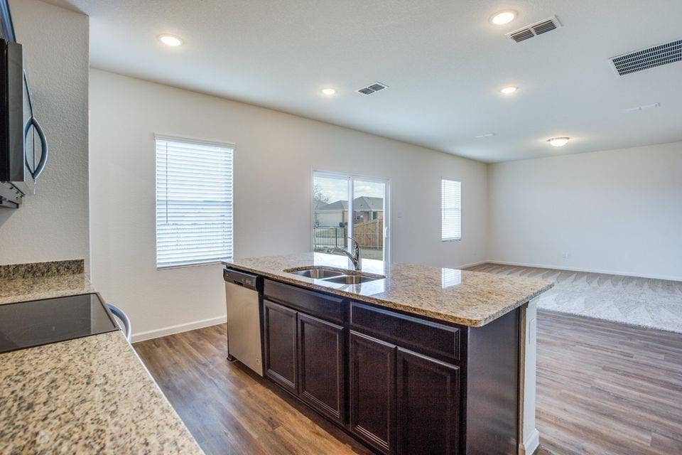 Kitchen island featuring a double-basin sink, stainless steel dishwasher, and granite countertop