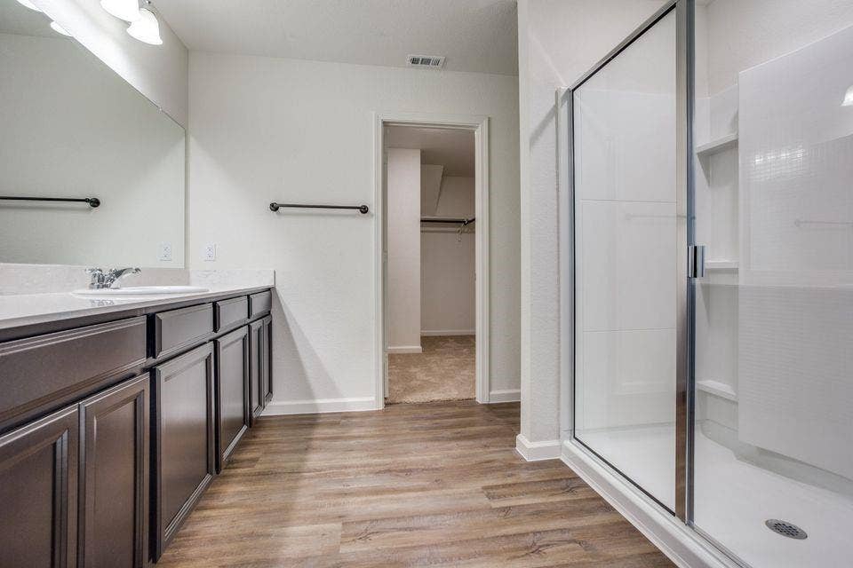 Bathroom featuring a wide vanity with dark cabinetry, a single basin sink, and a spacious mirror