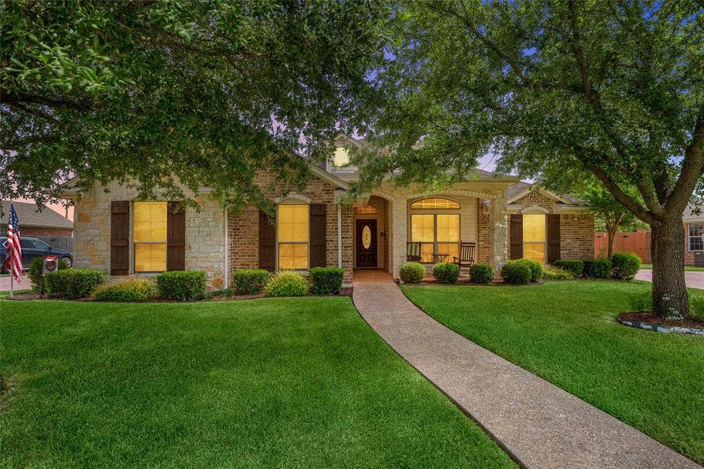 Stone and brick exterior featuring a covered entry, arched window, dark wood front door, and a concrete pathway