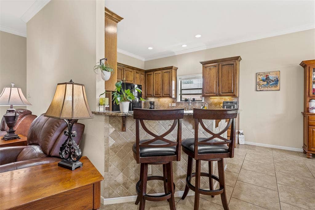 Kitchen bar area featuring a granite countertop, tiled backsplash, and recessed lighting