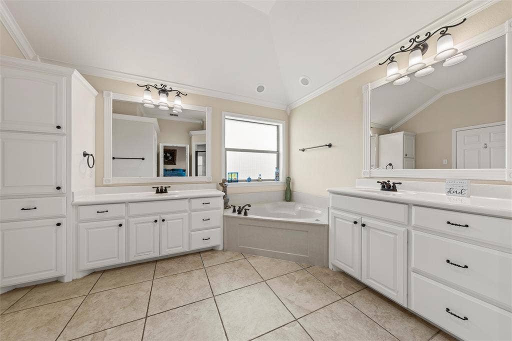 Bathroom featuring twin vanities with white cabinetry, white countertops, and framed mirrors