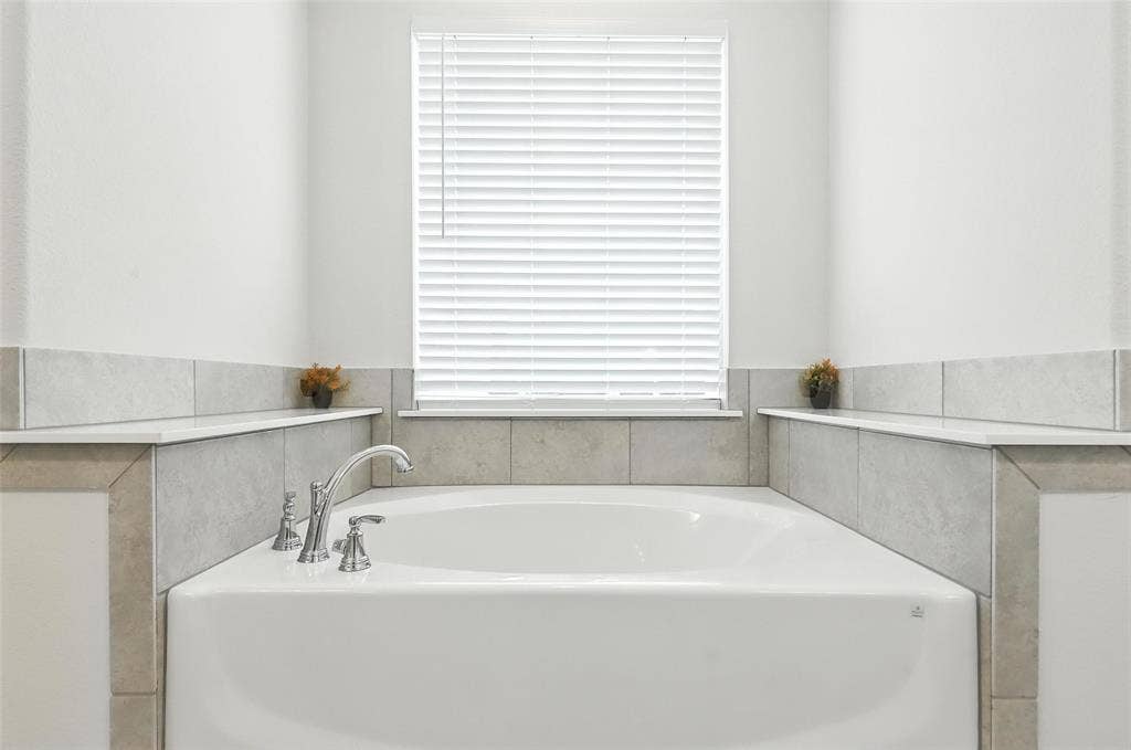 3141 Claire Drive, Midlothian, TX 76065 Built-in soaking tub featuring chrome fixtures, a tiled surround, integrated shelving, and a window with privacy blinds