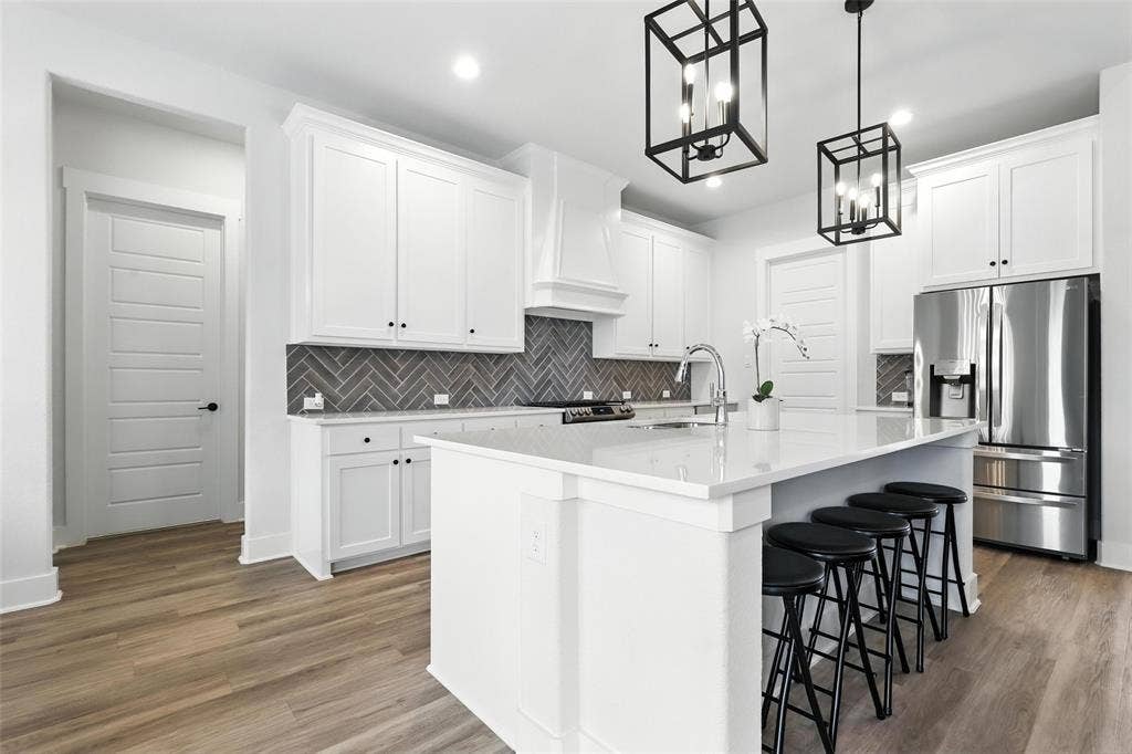 3141 Claire Drive, Midlothian, TX 76065 Modern kitchen featuring a large central island with seating, white shaker cabinetry, stainless steel appliances, and wood-finish flooring