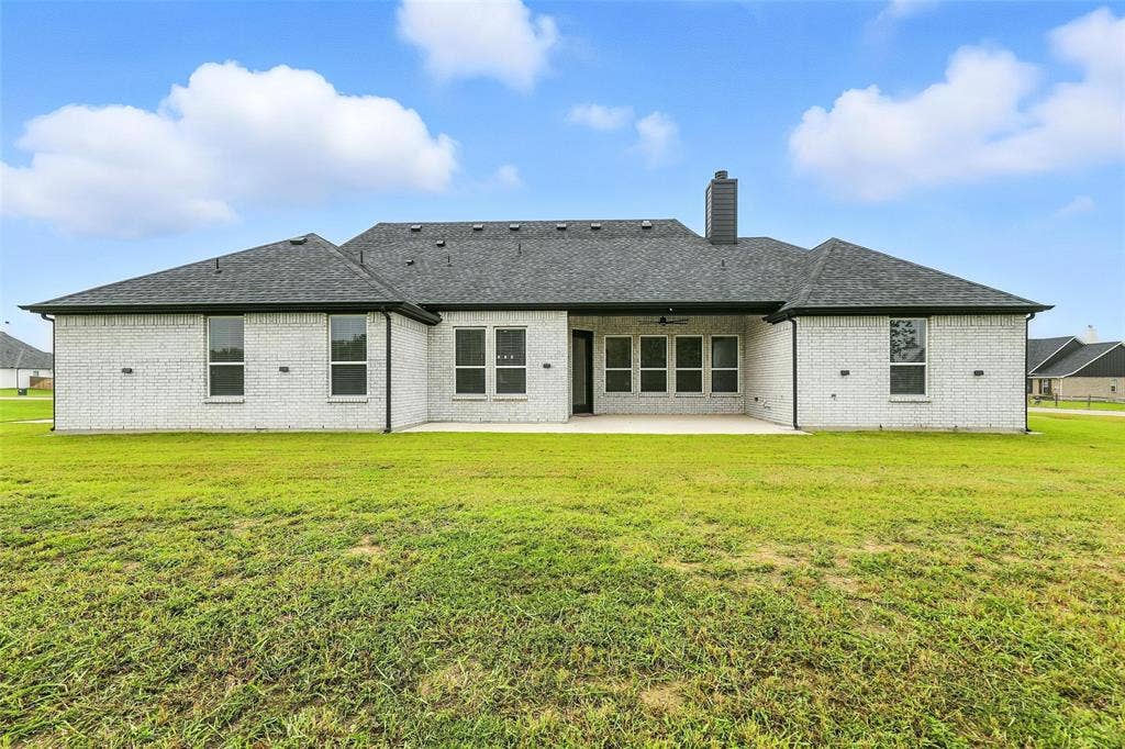 3141 Claire Drive, Midlothian, TX 76065 Spacious rear exterior featuring light-colored brick, dark shingle roofing, and a large concrete patio
