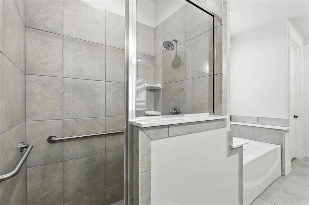 3141 Claire Drive, Midlothian, TX 76065 Contemporary bathroom featuring a tiled shower with glass enclosure, a built-in shower shelf, a showerhead, a separate soaking tub, and grab bars