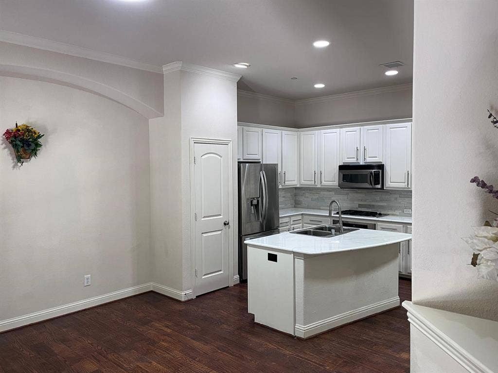 5717 PANTHEON Court, Plano, TX 75024 Modern kitchen featuring white cabinetry, stainless steel appliances, a center island with a sink, and wood-finish flooring