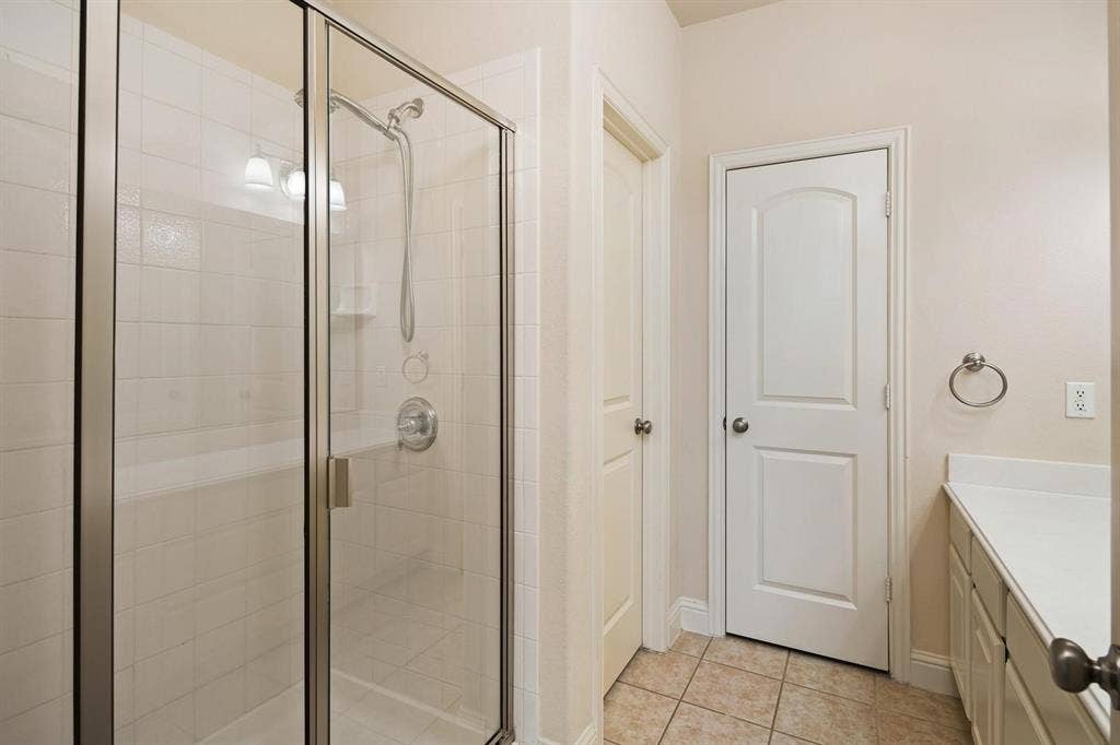 5717 PANTHEON Court, Plano, TX 75024 Glass-enclosed shower with white subway tile surround, built-in bench, and wall-mounted showerhead