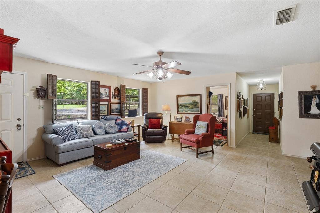 777 Wildwood Trail, Weatherford, TX 76085 Neutral tone tile flooring complements light wall tones in this spacious interior, featuring multiple windows with wood shutters, a ceiling fan with integrated lighting, and recessed entryway