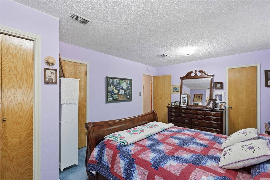 777 Wildwood Trail, Weatherford, TX 76085 Bedroom featuring light purple walls, wood-finish doors, a textured ceiling, and blue carpeting