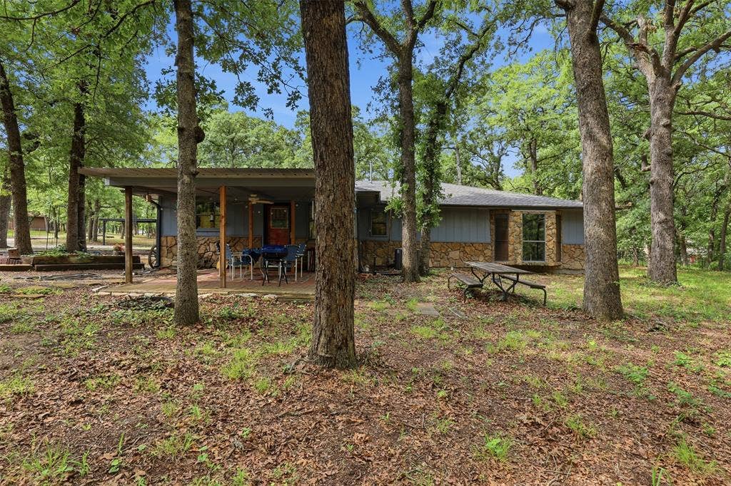 777 Wildwood Trail, Weatherford, TX 76085 Wooded lot featuring a stone and siding exterior with a covered patio