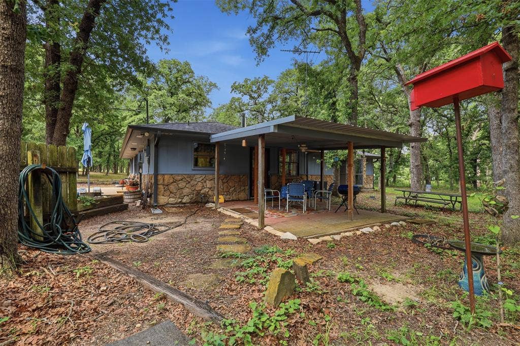 777 Wildwood Trail, Weatherford, TX 76085 Exterior property featuring a stone and siding facade, a covered patio, and surrounding mature trees