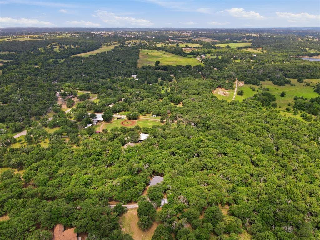 777 Wildwood Trail, Weatherford, TX 76085 Expansive aerial view showcasing a verdant landscape with extensive tree coverage and interspersed clearings