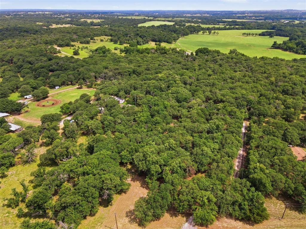 777 Wildwood Trail, Weatherford, TX 76085 Expansive acreage featuring abundant mature trees, open clearings, and a dirt track