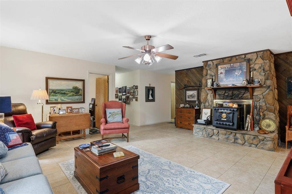 777 Wildwood Trail, Weatherford, TX 76085 Living area featuring a floor-to-ceiling stone fireplace with a substantial hearth and mantel, complemented by wood-paneled accent walls