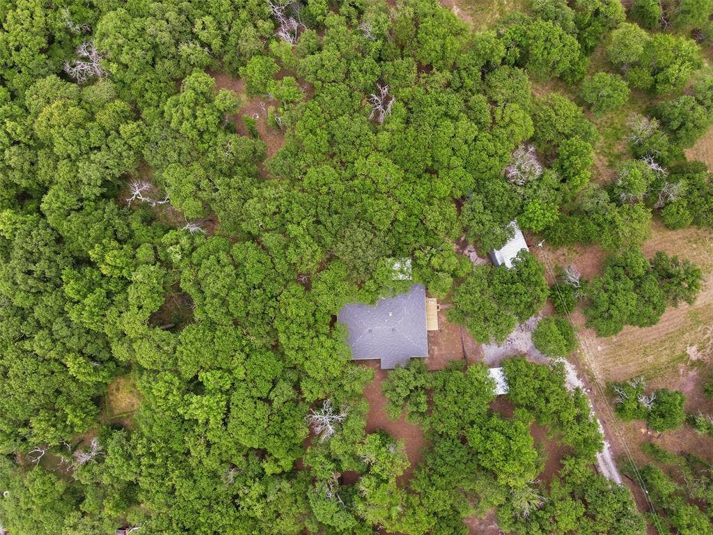 777 Wildwood Trail, Weatherford, TX 76085 Aerial perspective showcasing a property enveloped by dense, mature tree coverage
